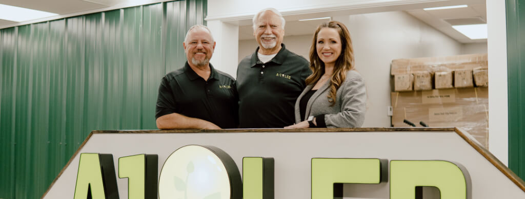 Senior executive team of A-1 LED, with founder Nelson Mears at the center, standing behind the company's branded reception desk in Arkansas, representing the brand's leadership and commitment to quality service.