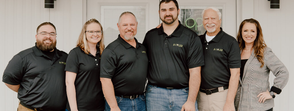 Friendly and professional team of an LED lighting company in Arkansas, standing in front of their office, ready to provide regional installation services