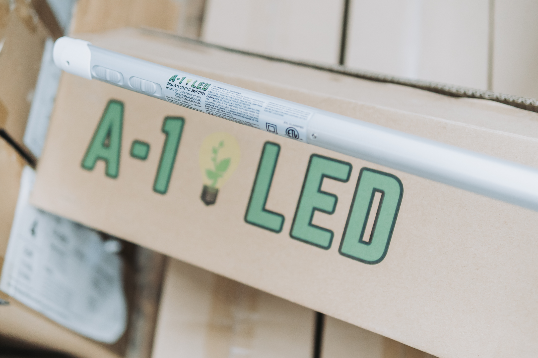 A cardboard box labeled A-1 LED with a small plant icon is shown. An LED tube light rests on top of the box, partially covering the label.