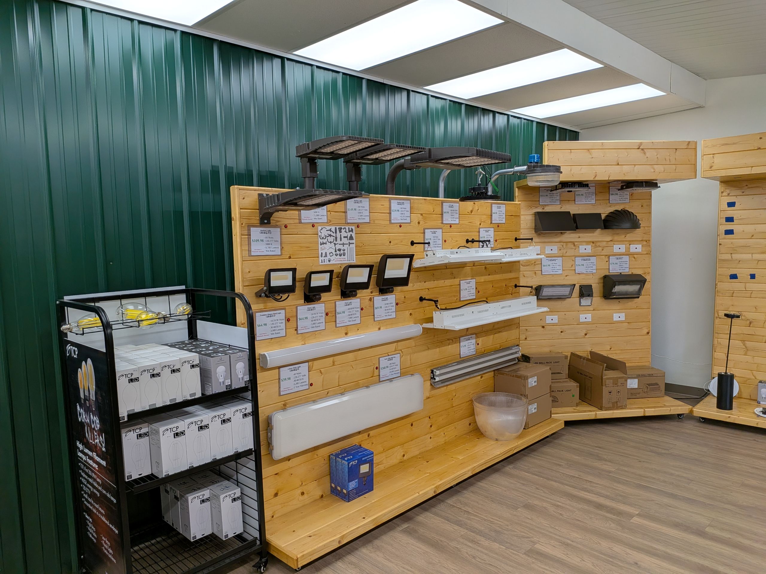 Reducing Maintenance Costs With High-Quality LED Lighting A retail display featuring various LED lights, including floodlights, wall packs, and linear fixtures. Boxes of LED bulbs are also visible, signifying the importance of led lighting maintenance
